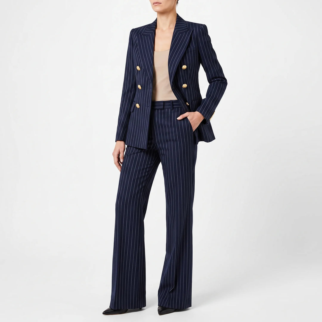 Model draagt een marineblauw gestreept damespak met gouden knopen en hoge taille broek.