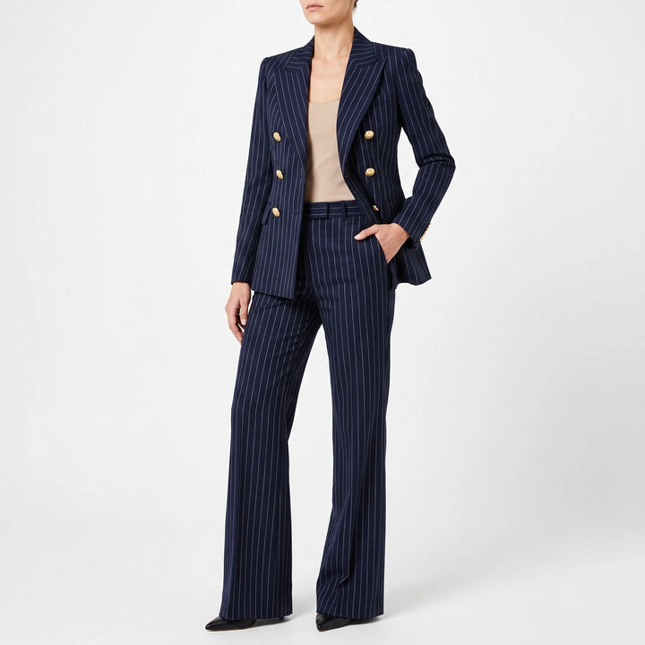Model draagt een marineblauw gestreept damespak met gouden knopen en hoge taille broek.