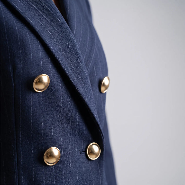 Close-up van de double-breasted blazer met verfijnde gouden knopen en streeppatroon.