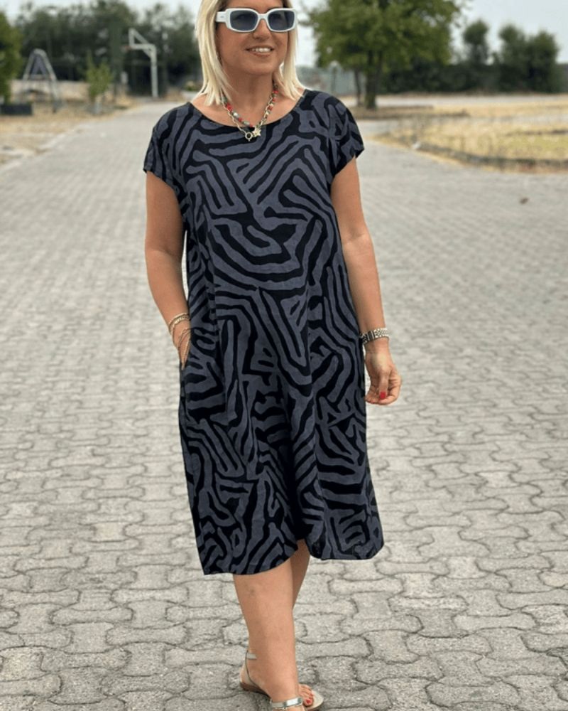 De halslijn en korte mouwen van de comfortabele zomerjurk, ideaal voor warme dagen.