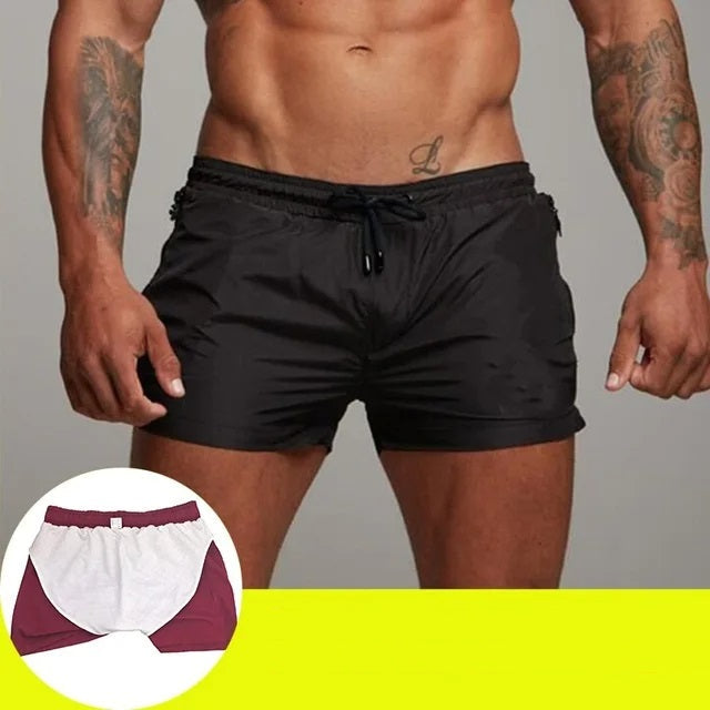Man draagt een zwarte sportieve zwemshort op het strand