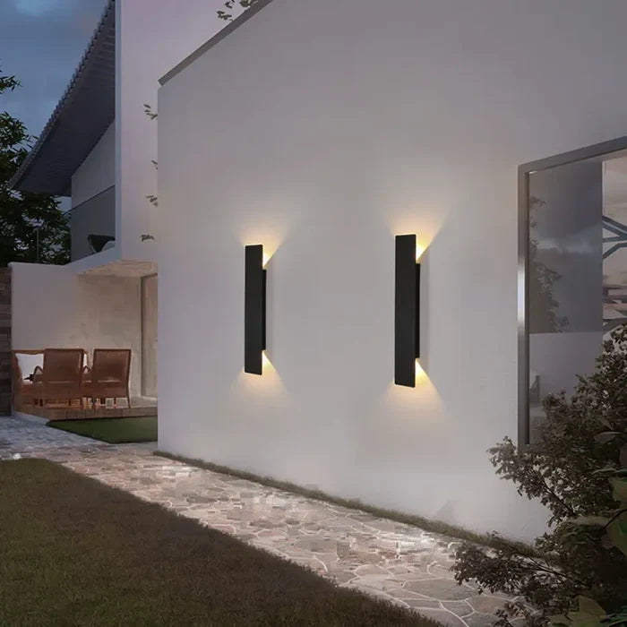 Twee zwarte StormGlow buitenlampen verlichten een tuinpad naast een huis.