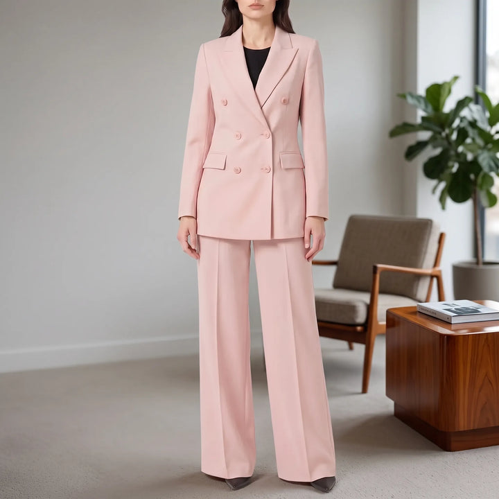 Vrouw draagt een elegant roze 2-delig damespak in een moderne kantooromgeving.