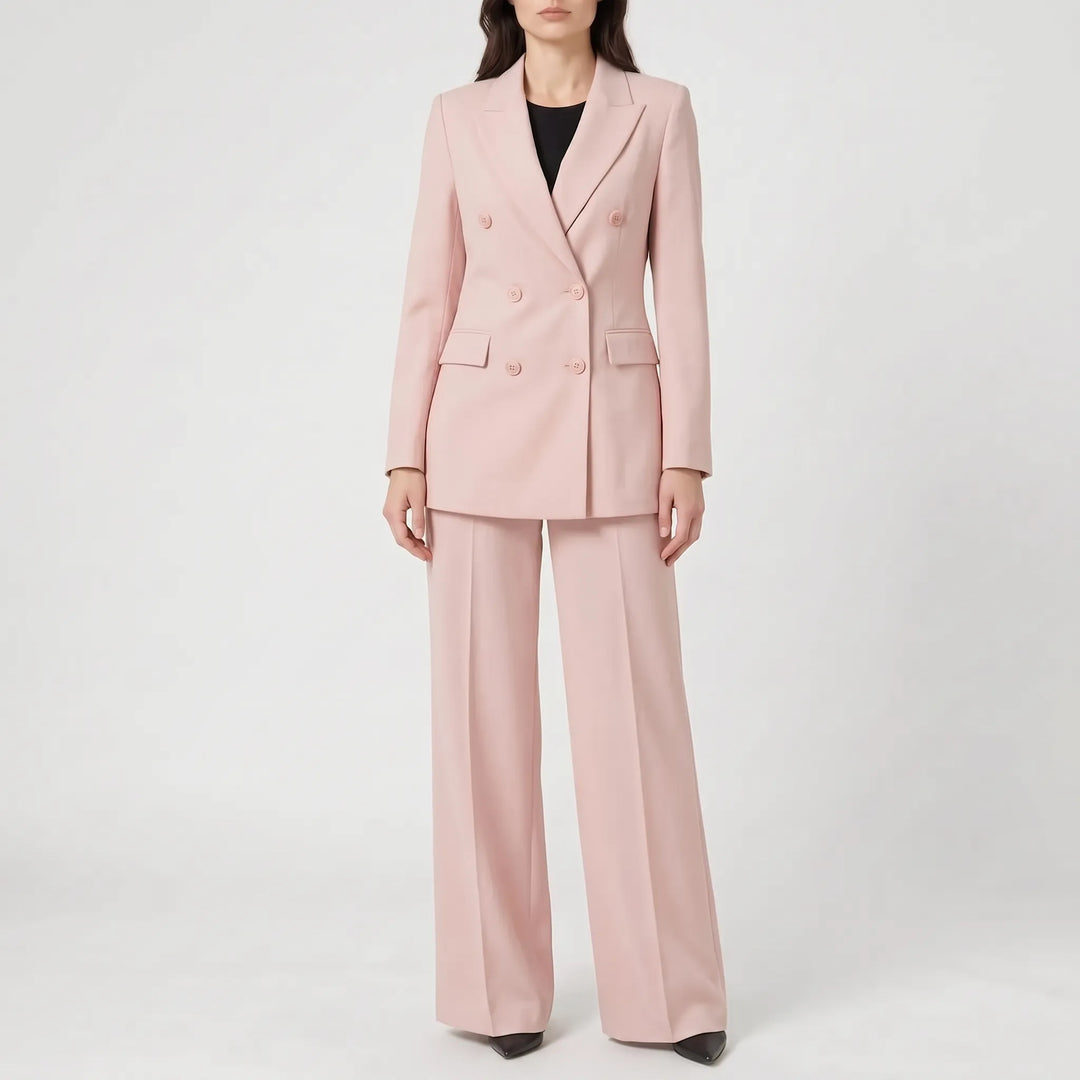 Model toont de rugzijde van het roze damespak, benadrukt de rechte pasvorm van de pantalon.