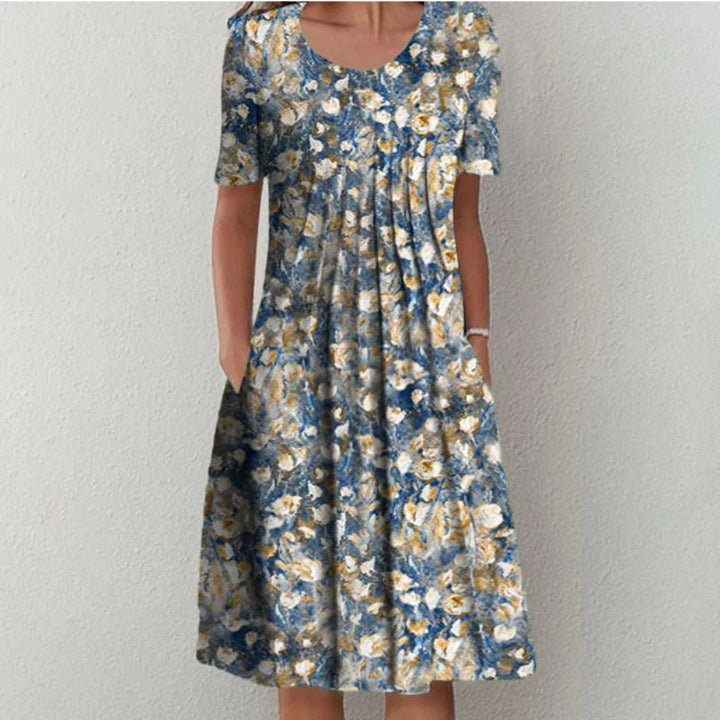 Comfortabele dames zomerjurk: midi lengte, v-hals, vrolijke bloemenprint en praktische zakken. Ideaal voor casual dagen.