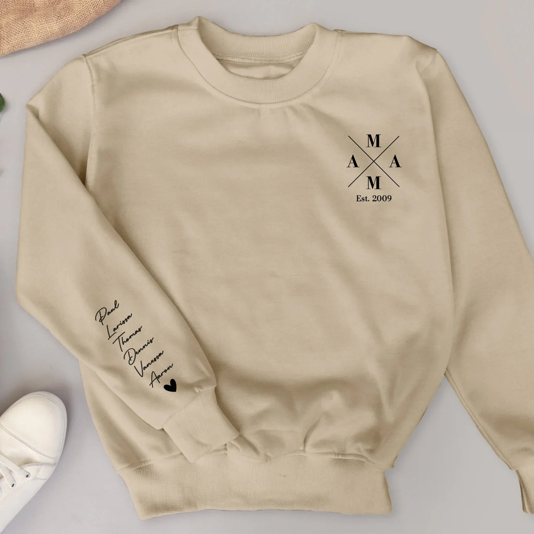 Beige damestrui met bedrukte mouw en witte sneaker ernaast