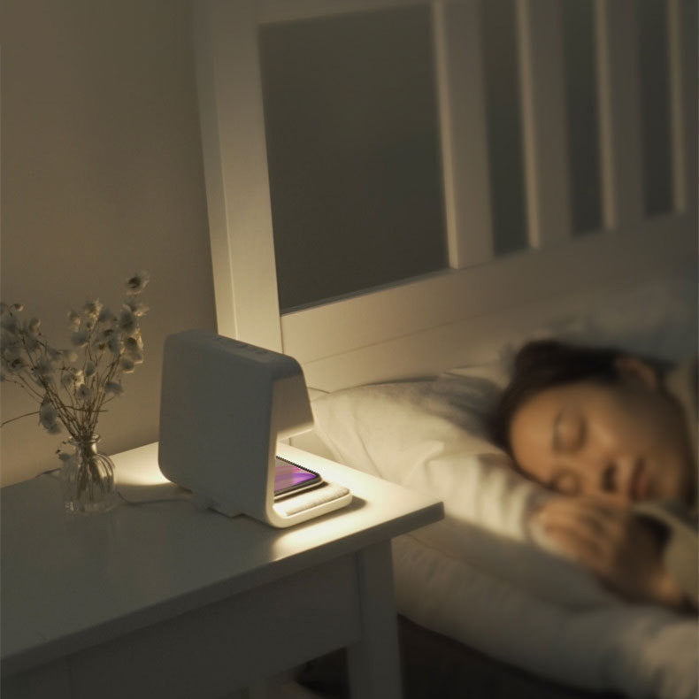 Witte multifunctionele tafellamp met LED licht, snelle telefoonoplader en wekker voor een opgeruimd bureau.