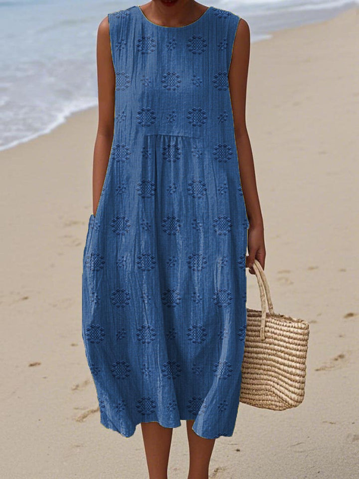 Vrouw draagt een blauwe vintage jurk met bloemmotief op het strand