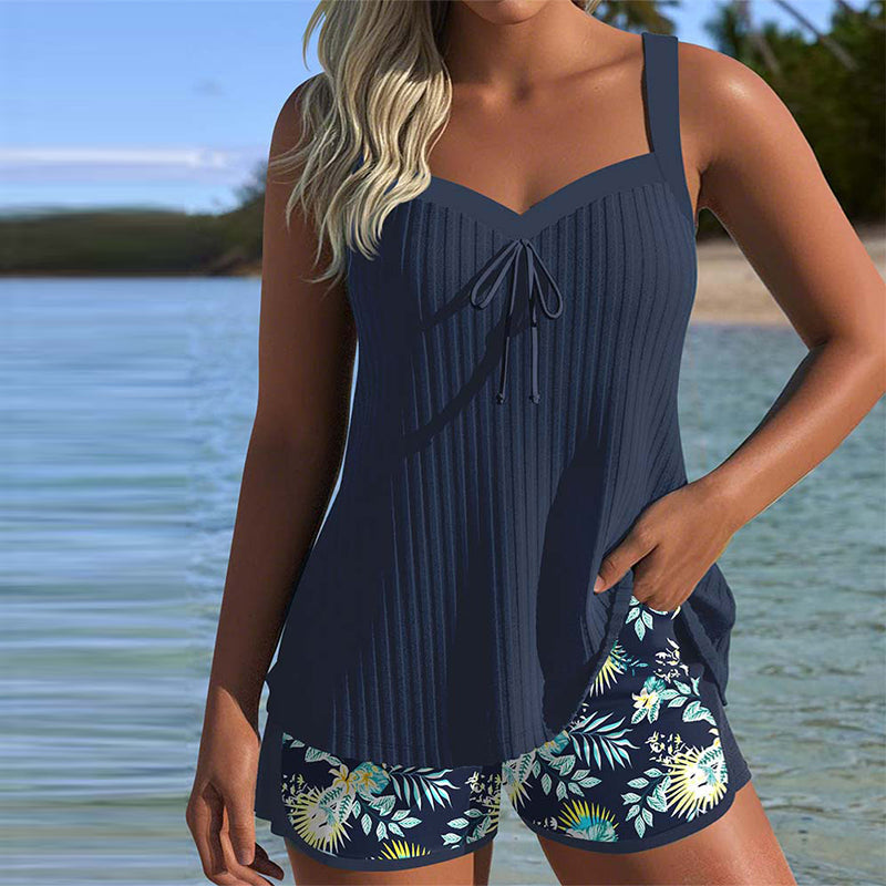 Model draagt marineblauwe Luna tankini set aan het water, toont voorkant.