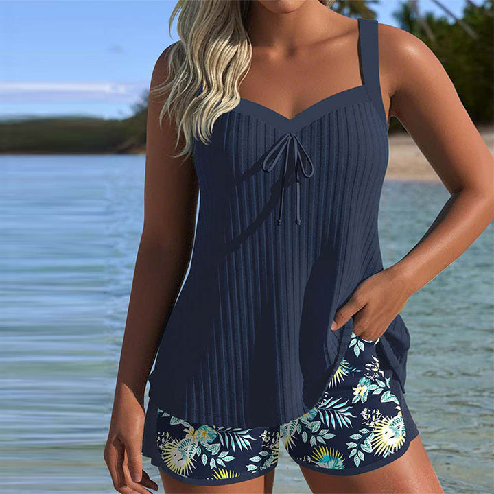 Model draagt marineblauwe Luna tankini set aan het water, toont voorkant.