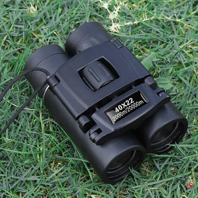 Opgevouwen 40x22 HD verrekijker liggend op groen gras, perfect voor onderweg.