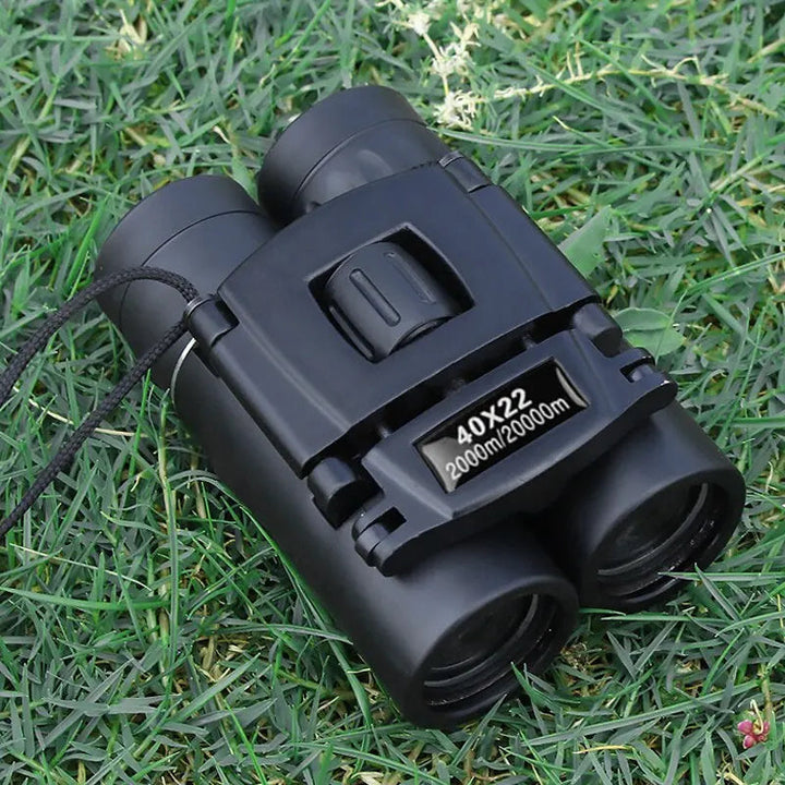Opgevouwen 40x22 HD verrekijker liggend op groen gras, perfect voor onderweg.