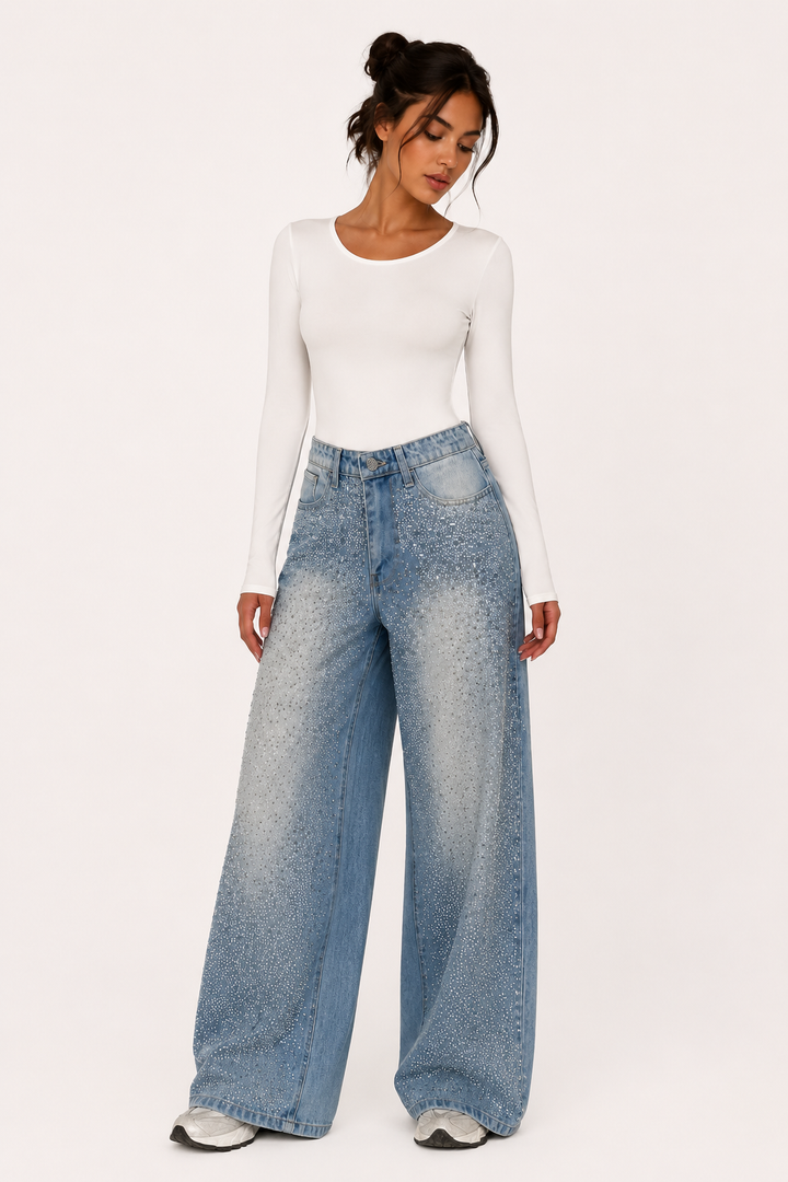 Model draagt blauwe damesjeans met wijde pijpen en strass-steentjes gecombineerd met een witte top.