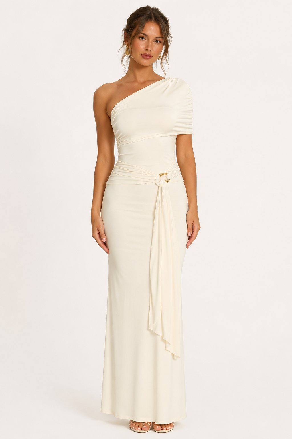 Vrouw in elegante witte lange gedrapeerde jurk met één schouder en gouden detail.