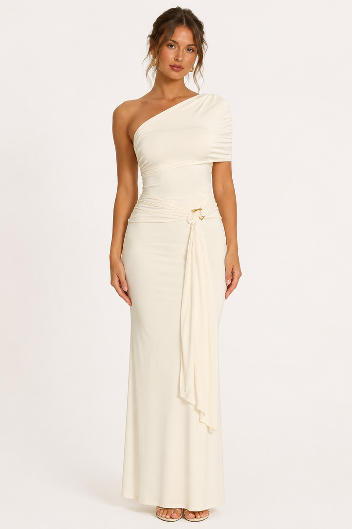 Vrouw in elegante witte lange gedrapeerde jurk met één schouder en gouden detail.