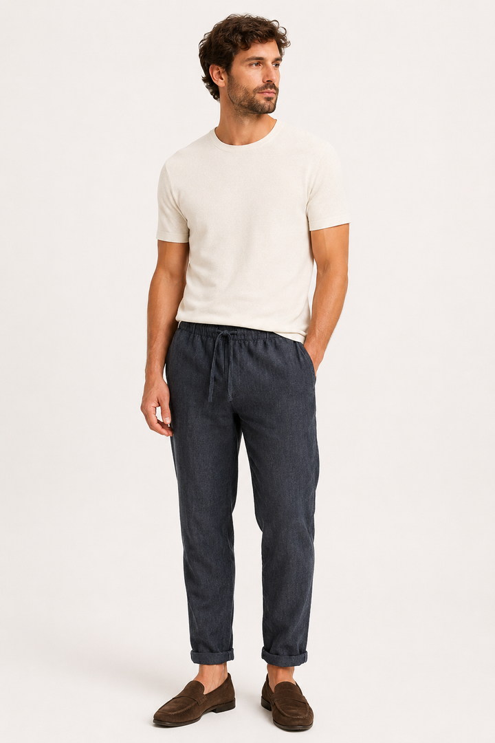 Man draagt donkere comfortabele zomerbroek met wit t-shirt en instappers