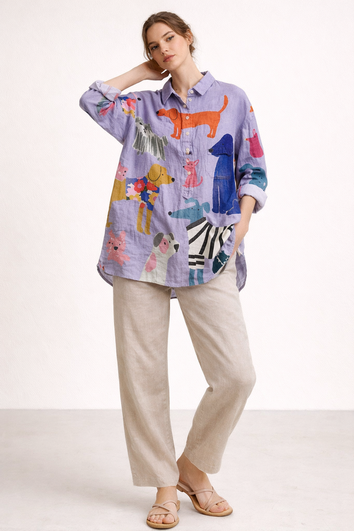 Model draagt een paarse damesblouse met veelkleurige, opvallende honden- en dierenprint.