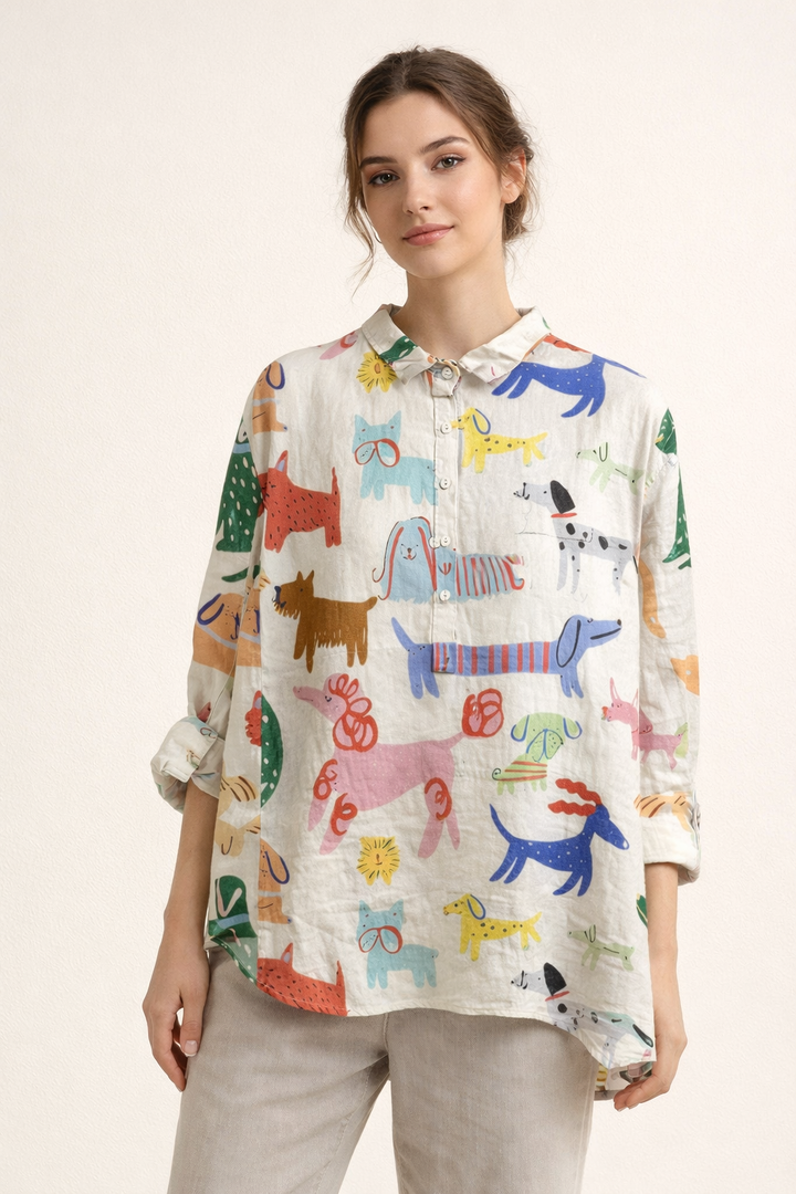 Model draagt een witte damesblouse met veelkleurige, vrolijke dierenprint en casual broek.