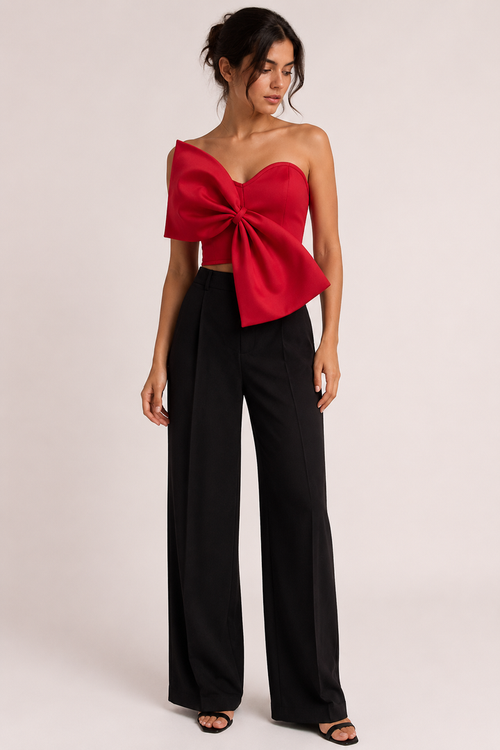 Vrouwelijke rode strapless korte top met grote strik gecombineerd met zwarte broek