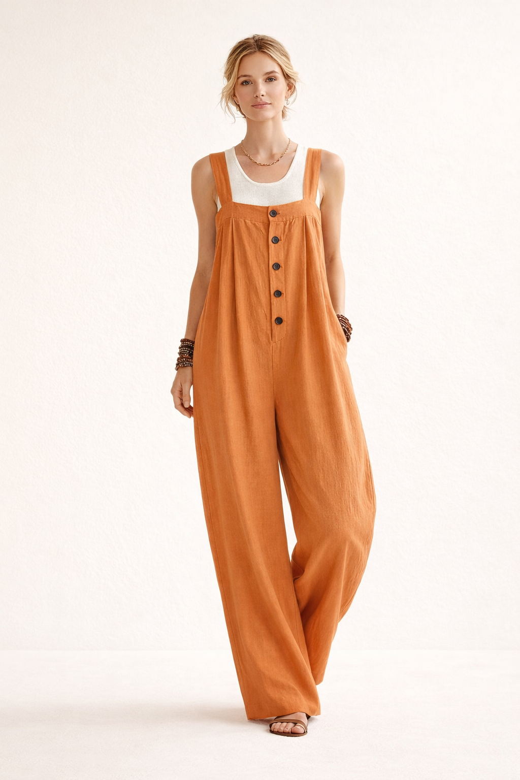 Model draagt een oranje lange jumpsuit met knopen aan de voorkant en brede banden