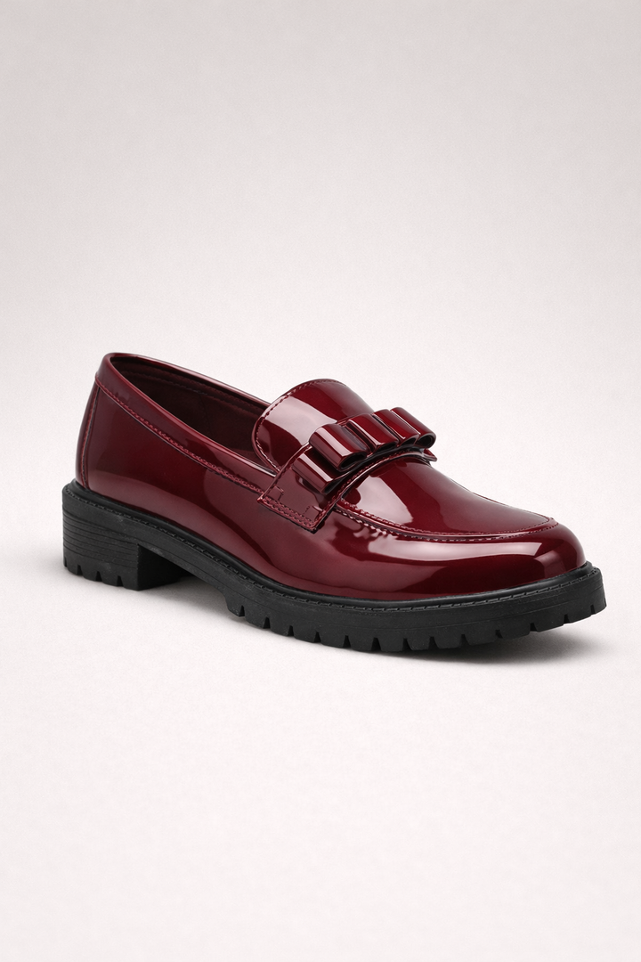 Rode loafer met grove zool en decoratieve details op lichte achtergrond