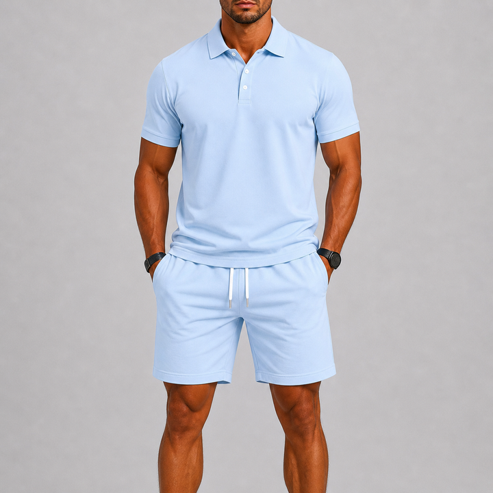 Mannelijk model met de handen in de zakken van de oranje sportshorts, toont de casual en comfortabele pasvorm van de set.