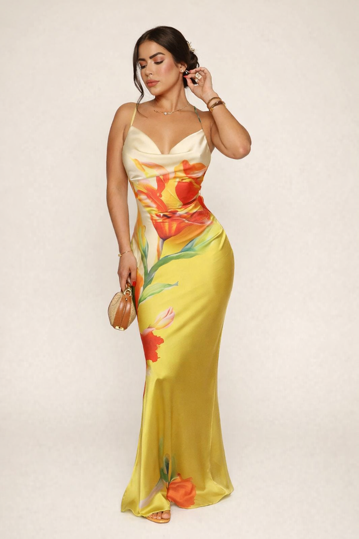 Model draagt een gele lange jurk met bloemenprint en spaghettibandjes