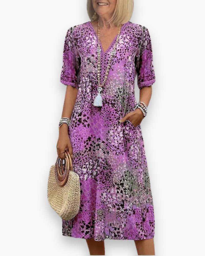 Model draagt een comfortabele dames midi-jurk met bloemenprint, V-hals en zakken. Perfect voor casual zomerse dagen.