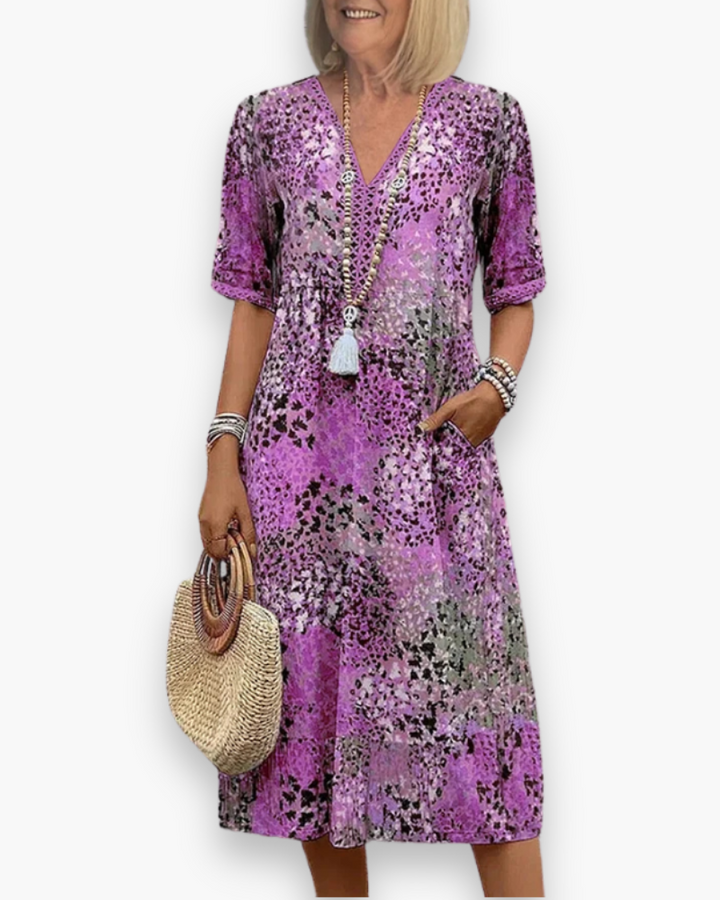 Model draagt een comfortabele dames midi-jurk met bloemenprint, V-hals en zakken. Perfect voor casual zomerse dagen.