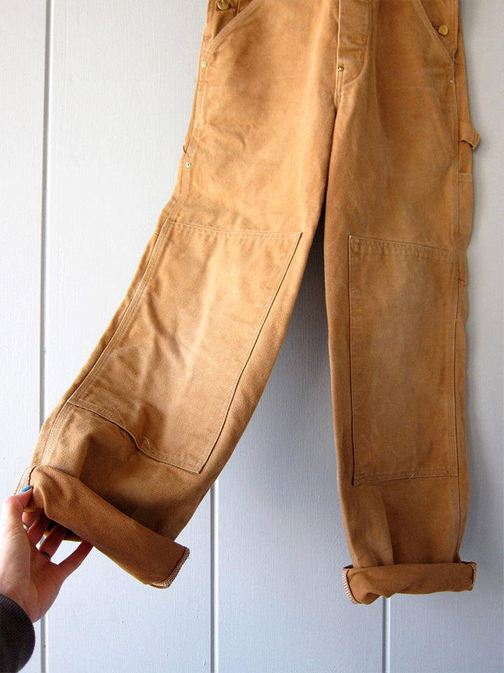 Robuuste canvas dungaree, unisex werk outfit in kameel, groen of zwart. Comfortabel en functioneel.