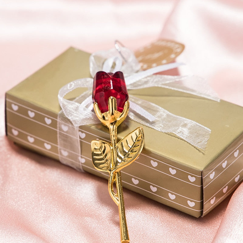Close-up van een rode glazen roos met gouden details rustend op een elegante geschenkdoos