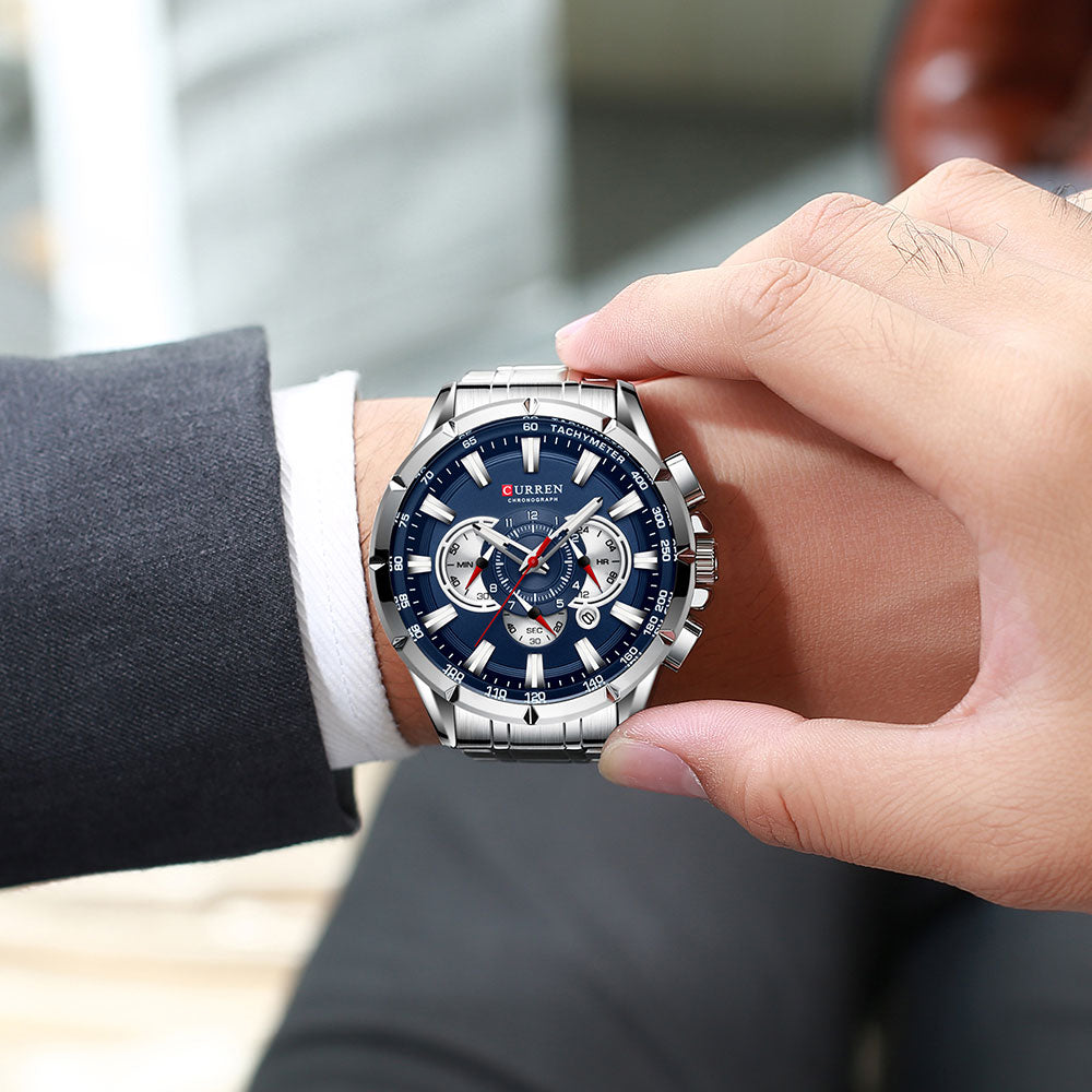 Man draagt het luxe herenhorloge met blauwe wijzerplaat, passend bij een zakelijke outfit.