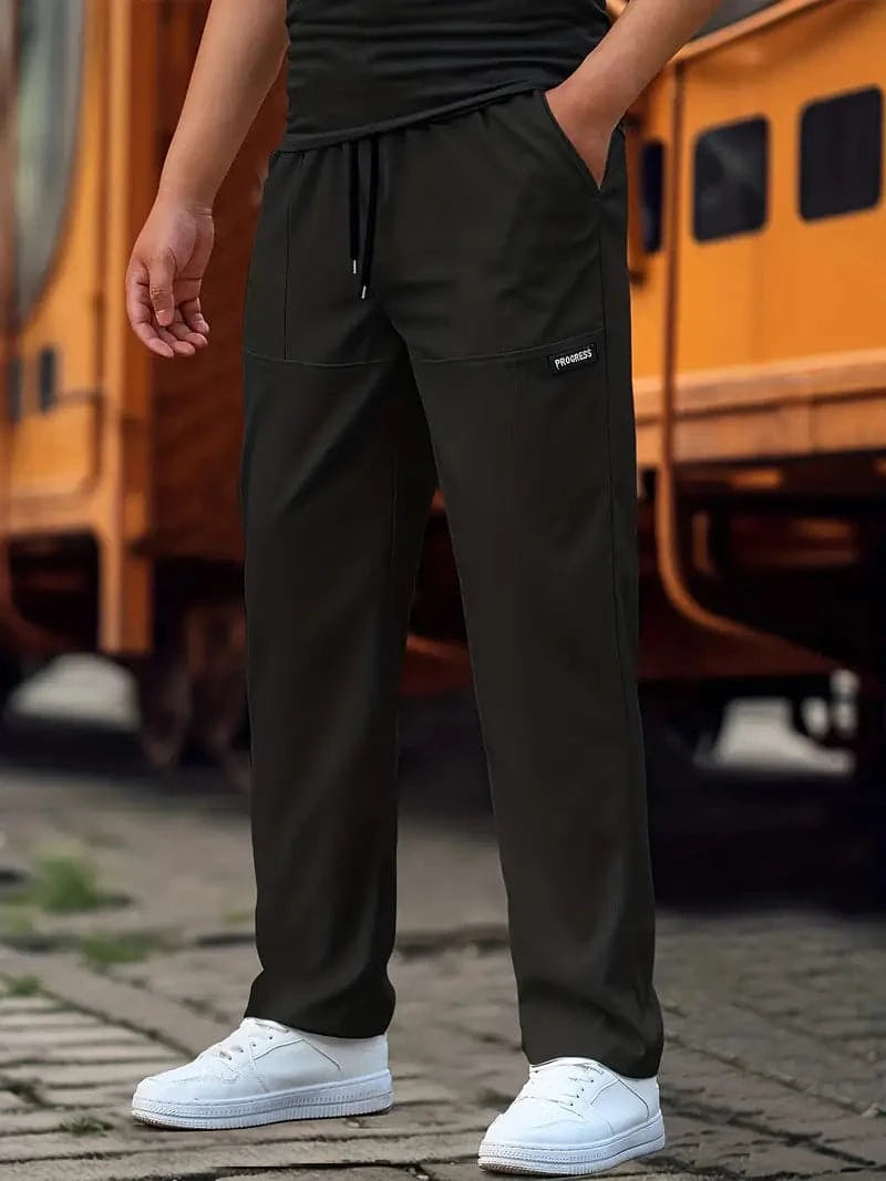 Heren joggingbroek in het zwart met een regular fit, gedragen met witte sneakers in een stedelijke setting.