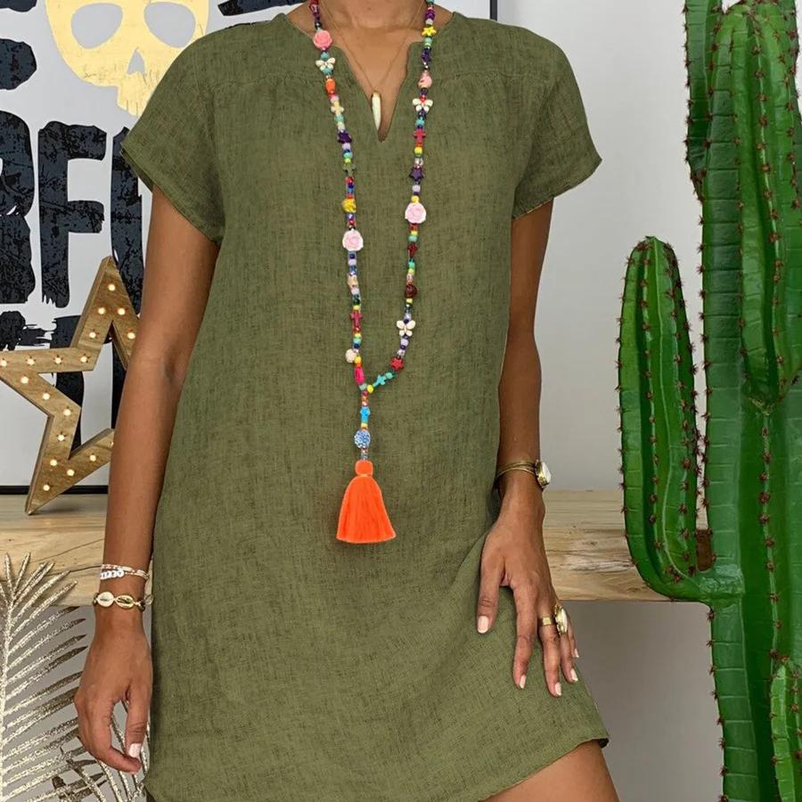 Vrouw draagt een groene zomerse mini-jurk met V-hals en kleurrijke ketting