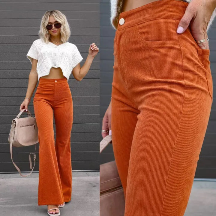 Vrouwelijke model draagt een oranje flared broek in corduroy stijl met witte top