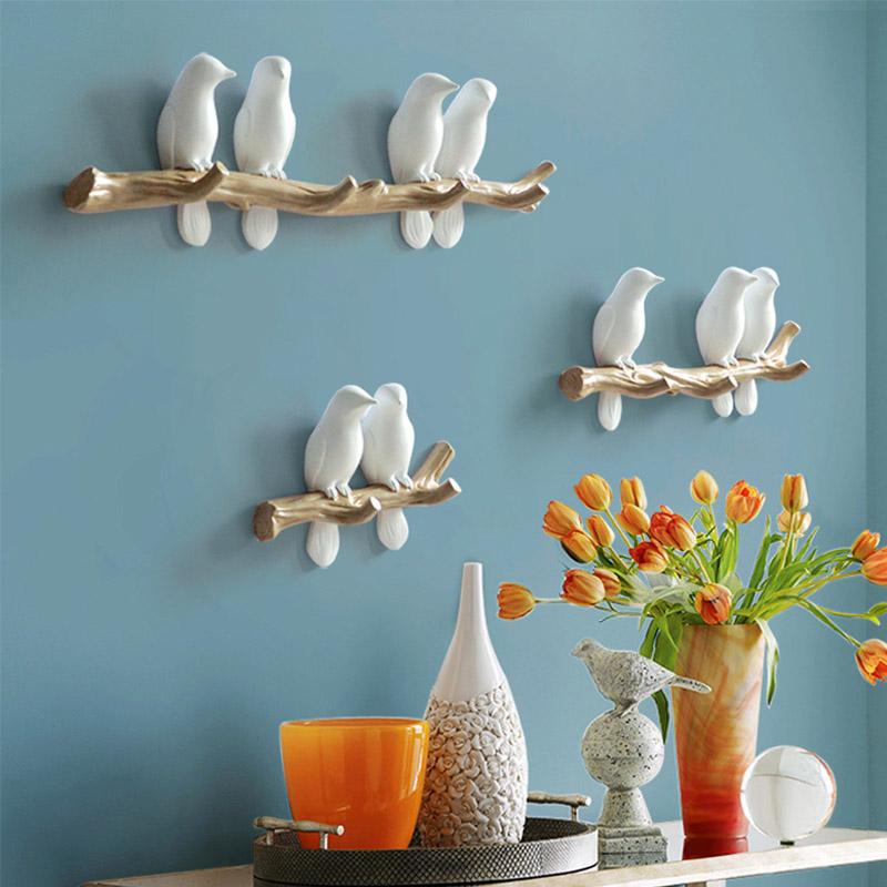 Roze vogels wandkapstok aan een neutrale muur, geschikt voor een kinderkamer of hal.