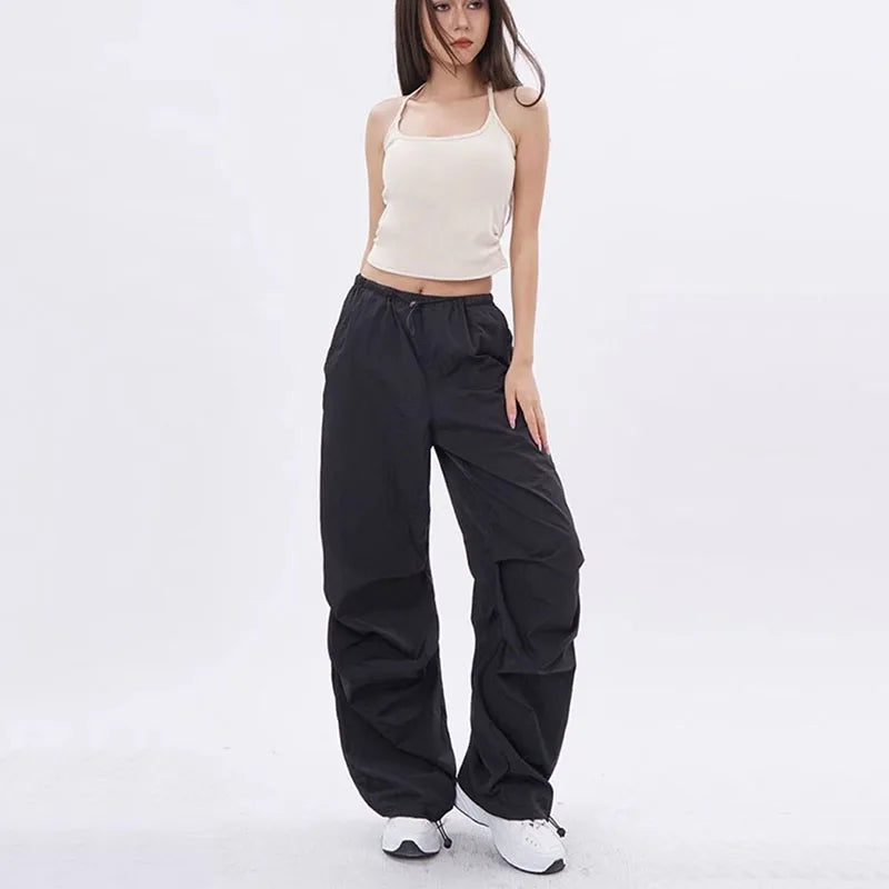 Model draagt zwarte baggy parachute broek met elastische taille en diepe zakken