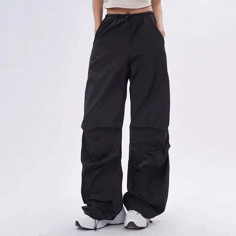 Zwarte dames oversized parachute broek in streetwear stijl gecombineerd met witte sneakers