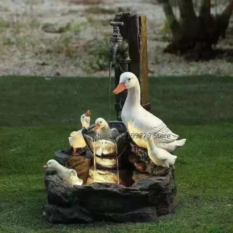 Solar fontein met witte eend en drie eendjes aan een kraan, verlicht door LED.