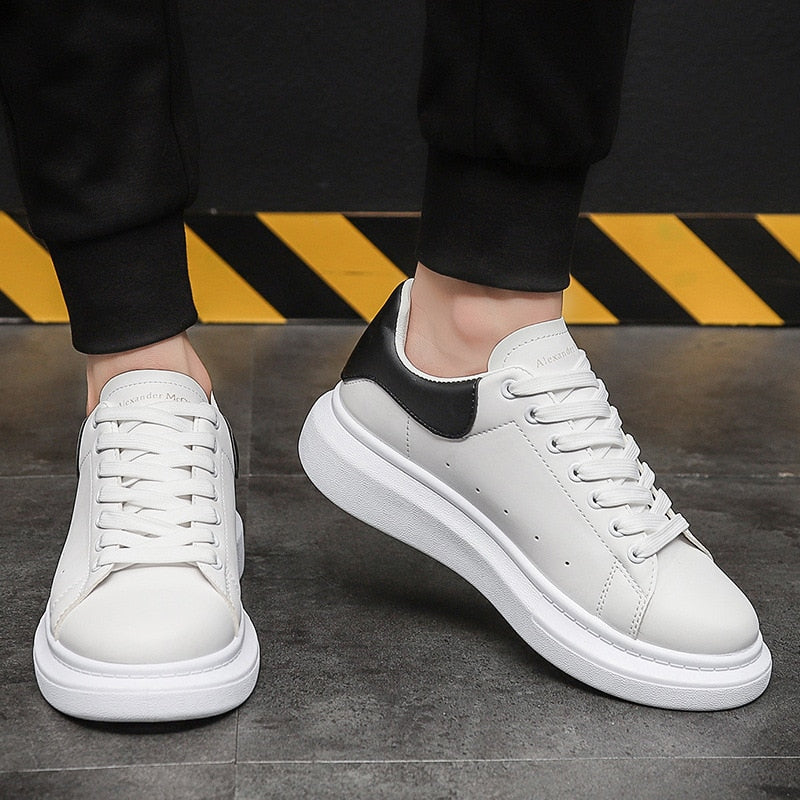 Heren urban sneakers in wit en zwart gedragen onder een zwarte broek