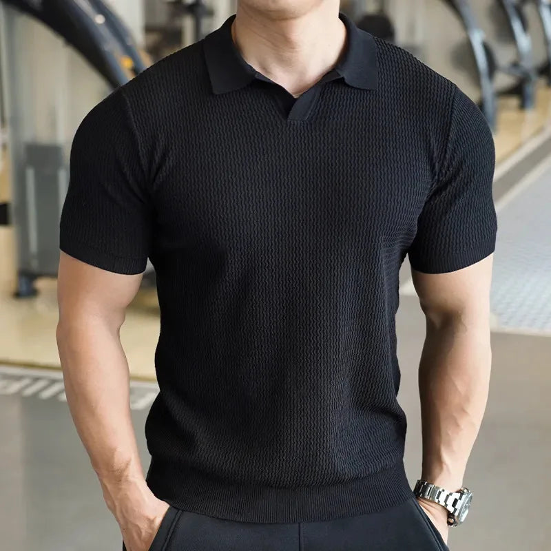 Man in een zwart poloshirt met korte mouwen in een moderne setting.