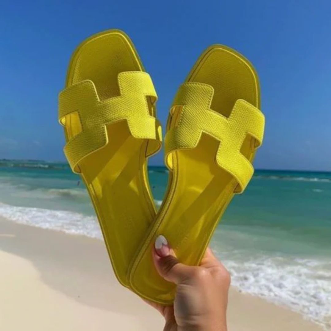 Gele trendy zomerdames sandalen op het strand