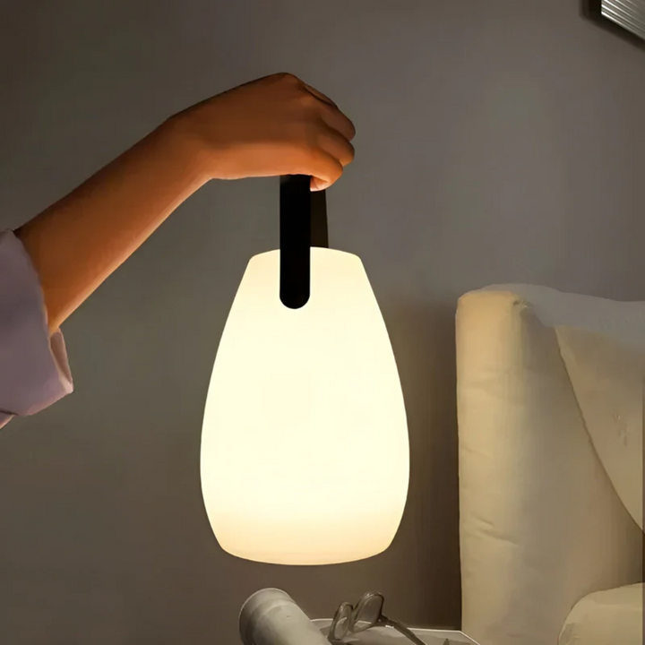 Draadloze tafellamp met handvat handmatig gedragen in een moderne slaapkamer