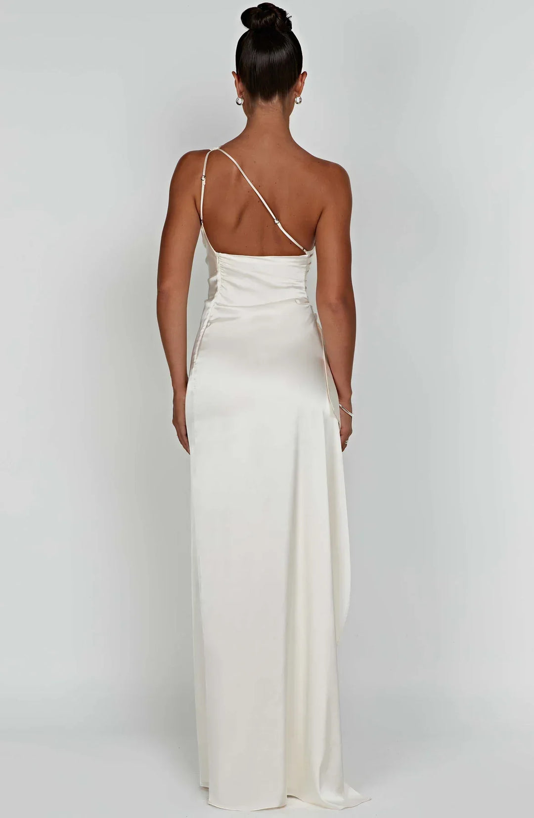 Stijlvolle witte dames satijnen maxi jurk met geplooide details en open schouder met split.