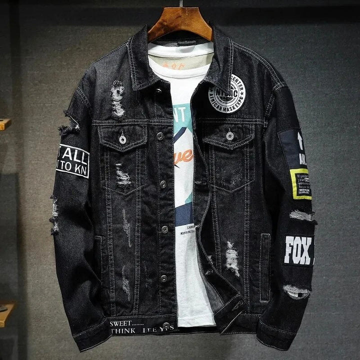 Zwarte heren denim jas met stoere rafels en patches hangend aan een hanger