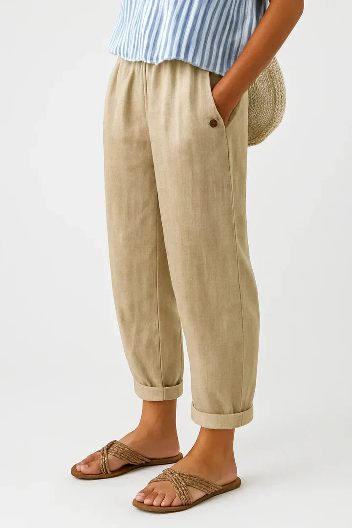 Dames relaxed fit broek in beige met enkellengte en opgerolde pijpen, gedragen met sandalen.