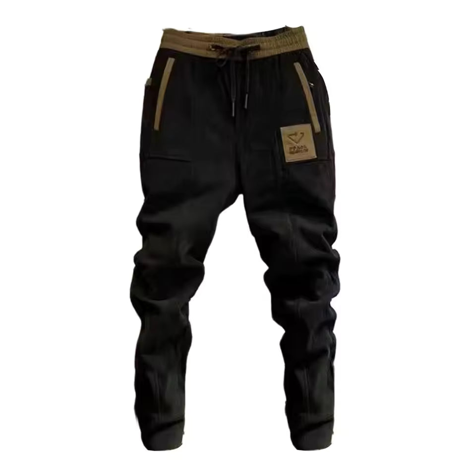 Zwarte herenbroek van corduroy met cargozakken, liggend gefotografeerd.