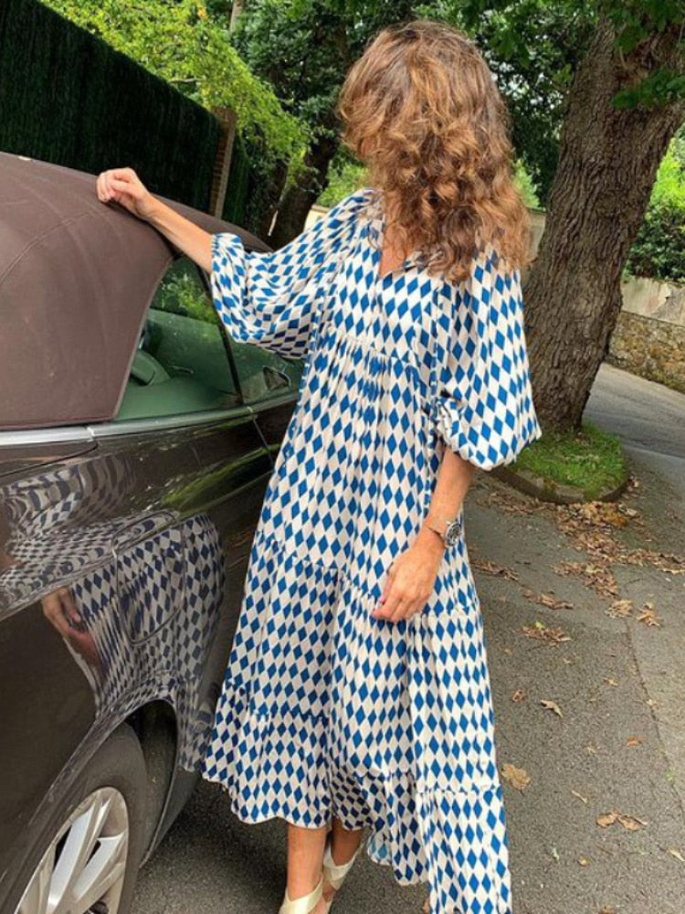 Model draagt een lange bedrukte dames maxi jurk Aurelia met sierlijke tailleband en vloeiende rok.