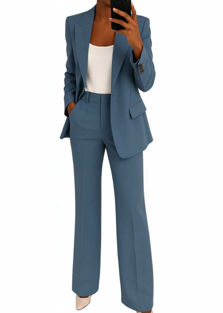 Vrouw draagt een blauwe dames blazer en broek set met wijde pijp en telefoon voor de spiegel