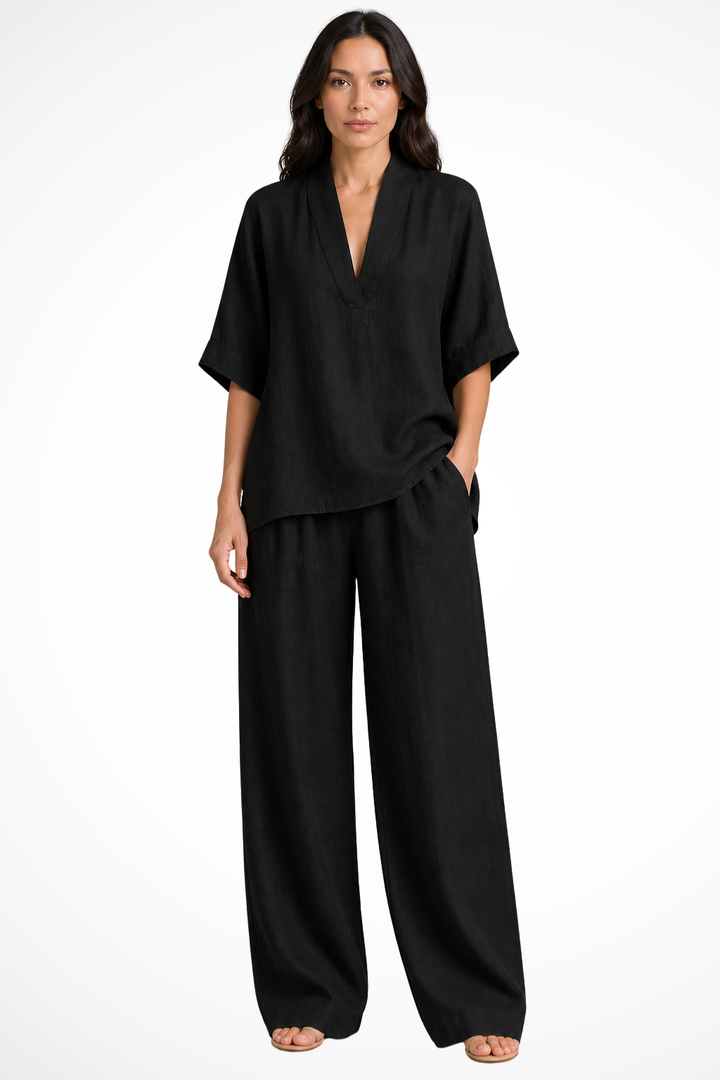 Model draagt een zwarte oversized tweedelige set met V-hals top en wide leg broek